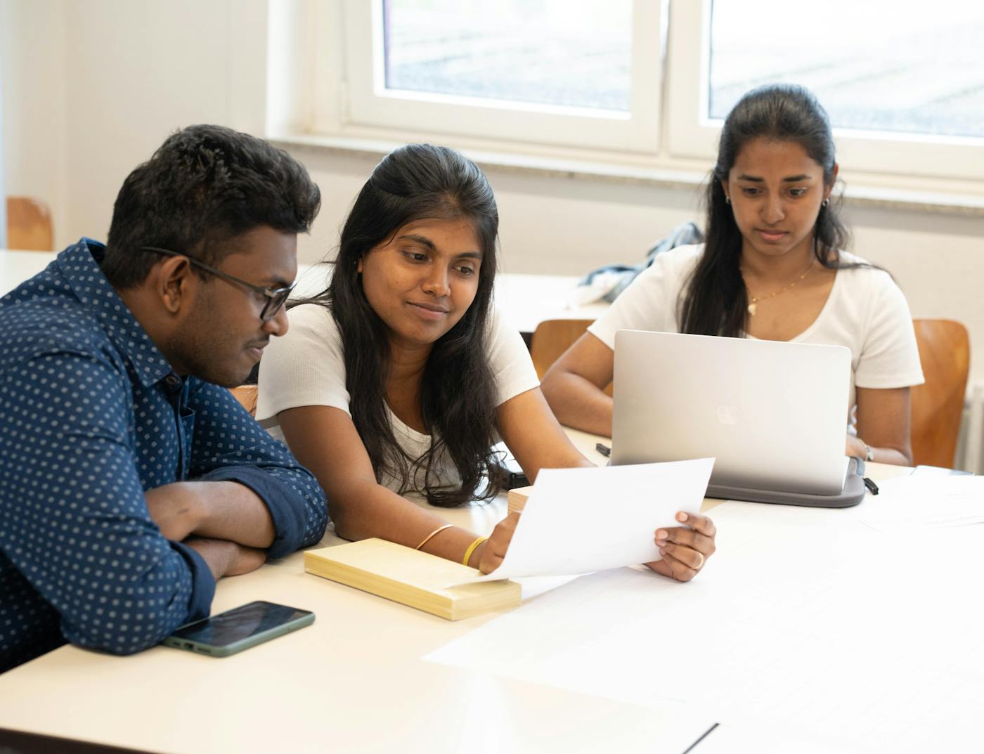 Indian students reviewing papers and a laptop for a scholarship application