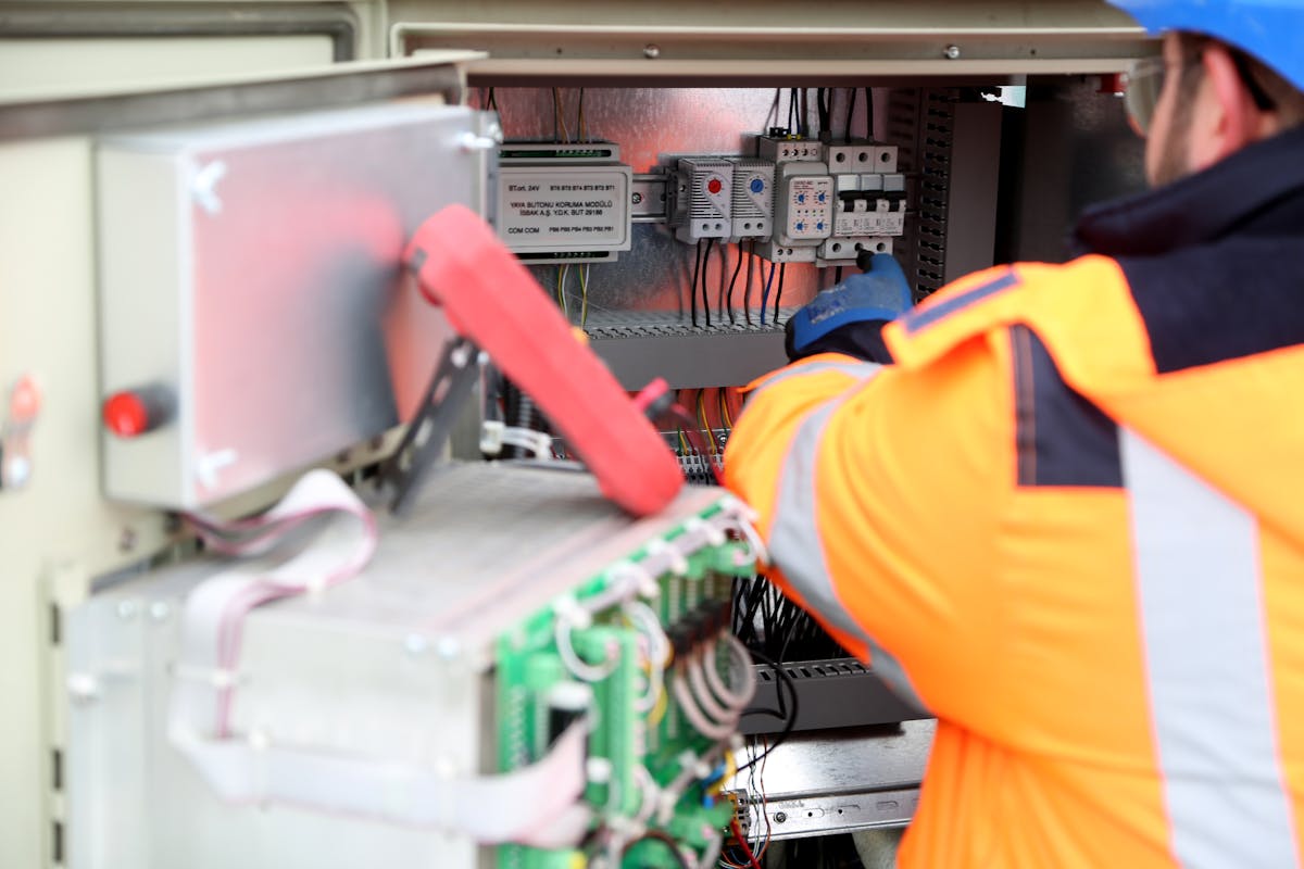 Indian electrician maintaining a switchboard in a Kuwait facility-services workshop