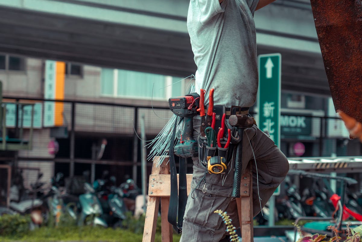 Indian facility-management technician on a ladder at a Doha residential tower whose ITI trade certificate needs Qatar