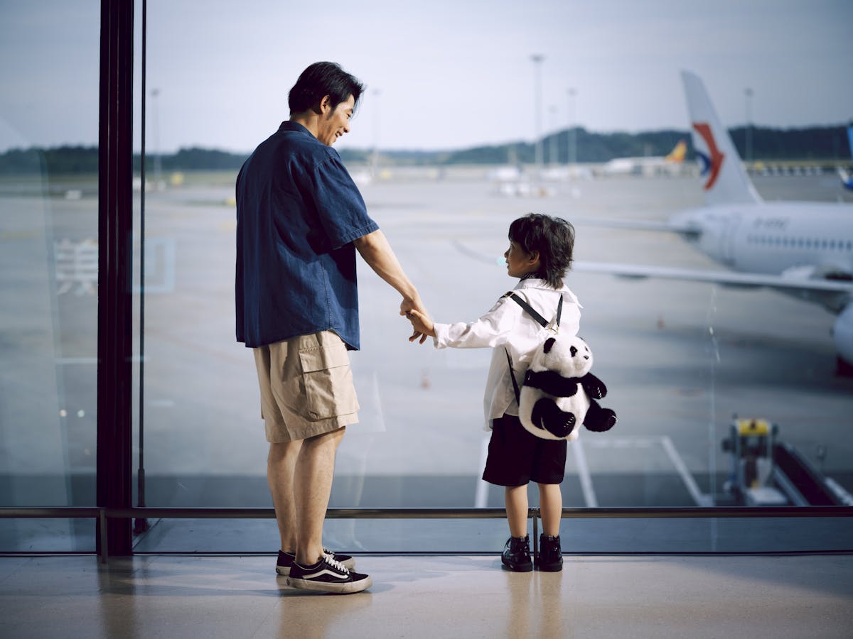 Indian father and son at an airport gate before the first international flight, a first-generation migrant family whose