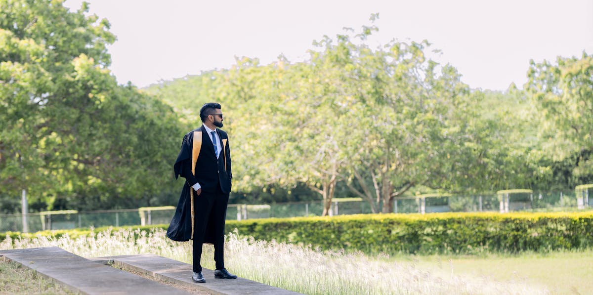 Indian graduate in cap and gown on a US university campus walkway