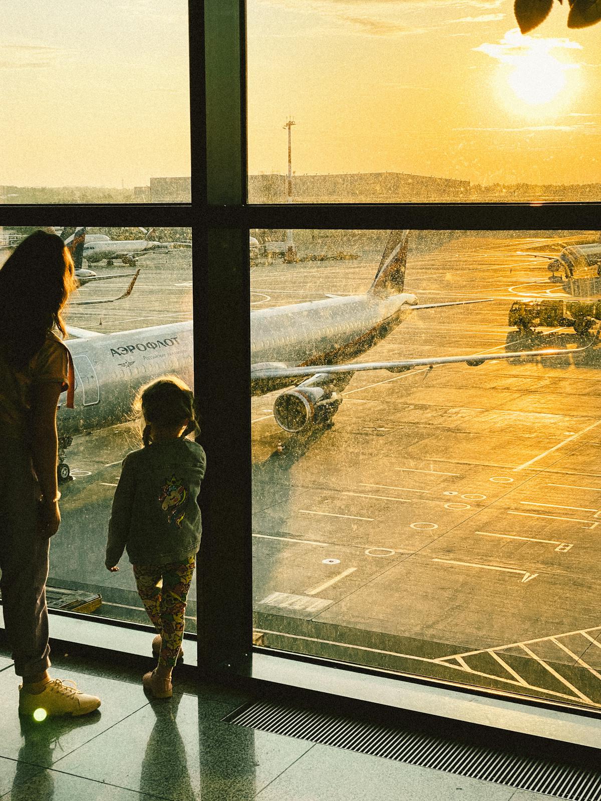Indian mother and daughter at an airport viewing area before their flight to Saudi Arabia
