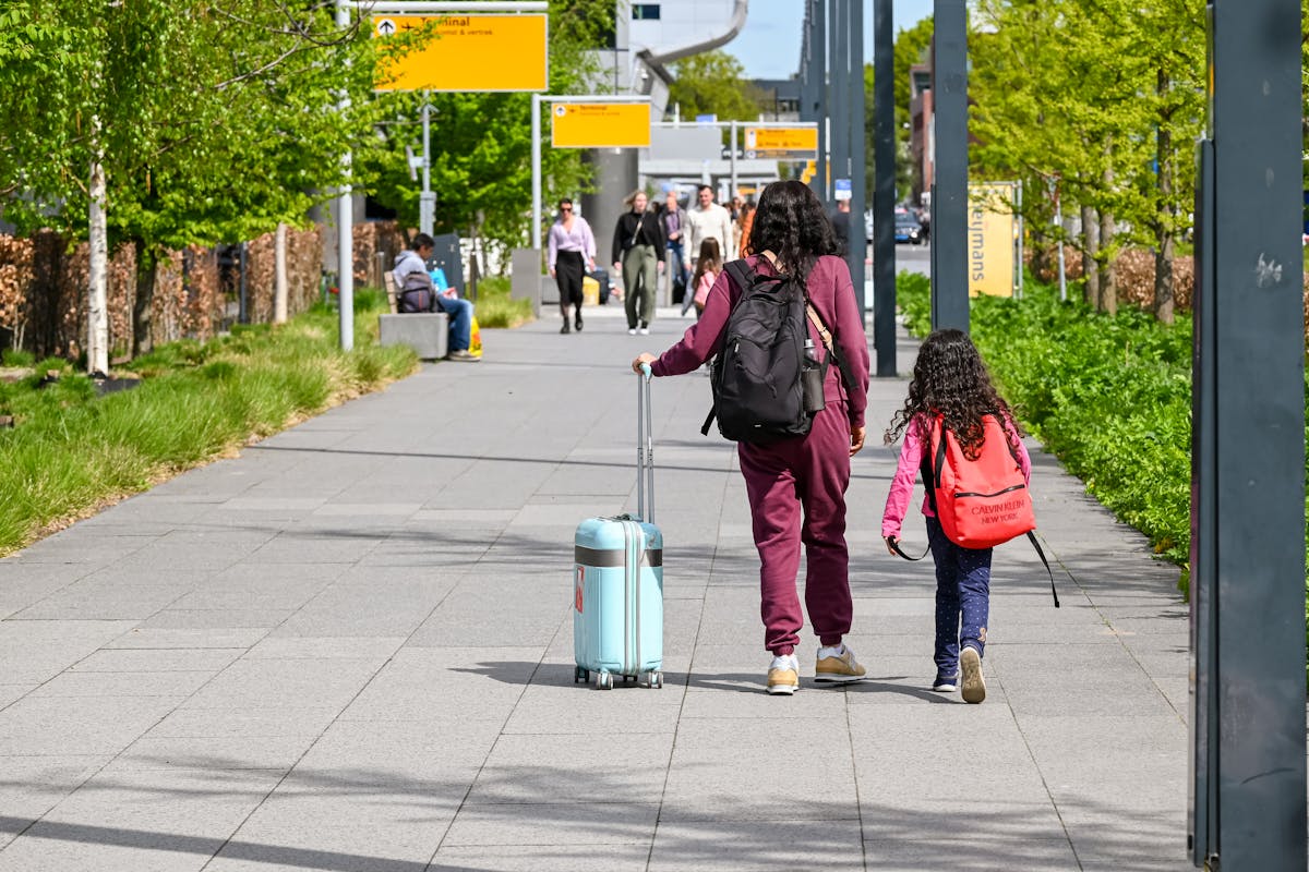 Indian mother and daughter walking with luggage outside an Australian airport