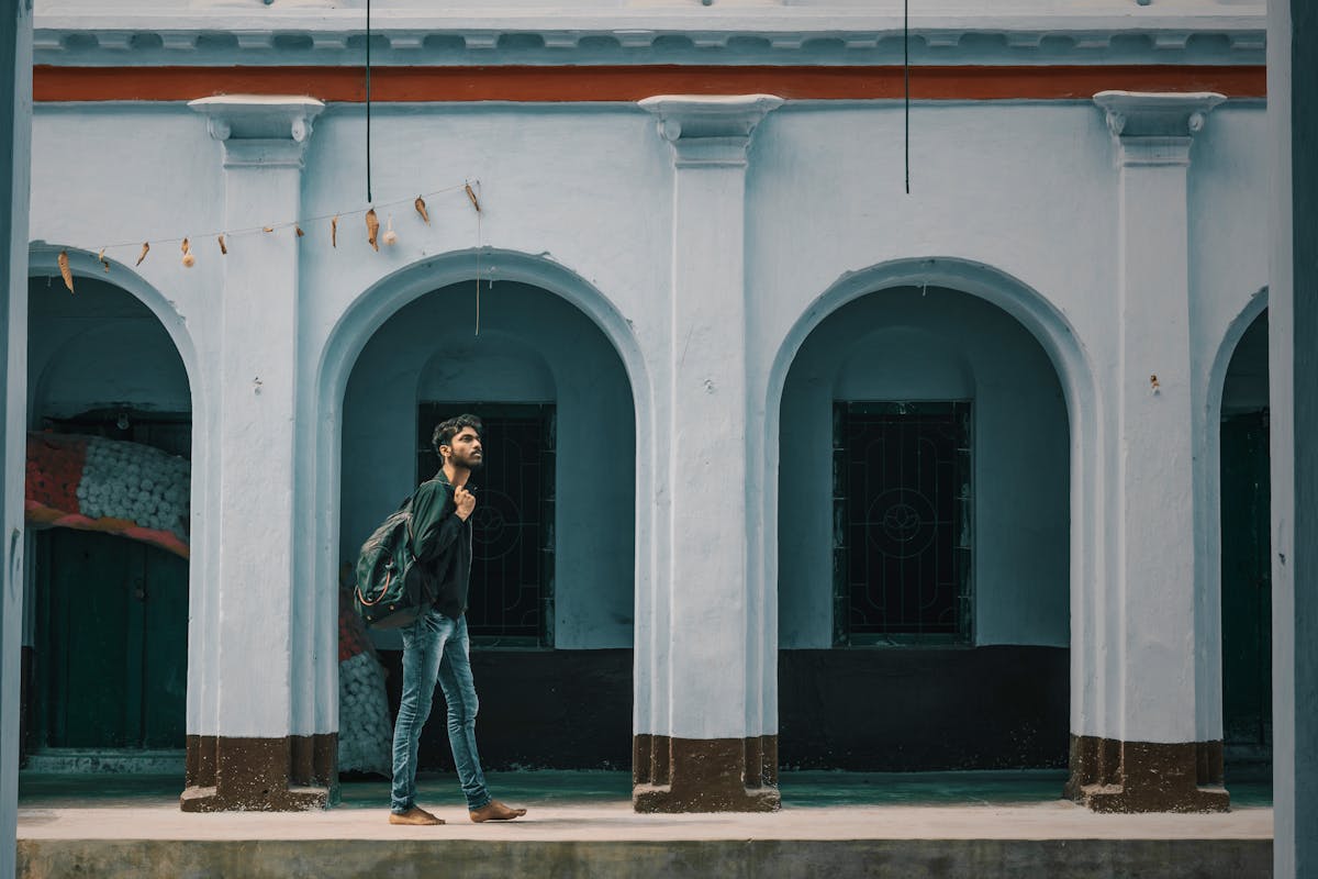 Indian student walking past historic university architecture in an Italian campus city, where a degree needs MEA
